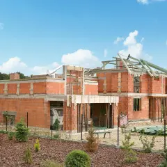 Rozbudowa domu w bok, projekty w trakcie realizacji. Dom z cegły, widoczna konstrukcja dachu i fundamenty.