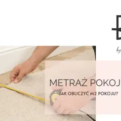 Dłoń mierzy taśmą dywan przy białej listwie przypodłogowej.