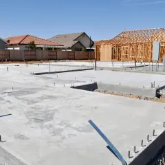 Fundamenty domu w budowie. Betonowe płyty i zbrojenie czekają na kolejne etapy budowy. Chudziak co to? To warstwa chudego betonu, która stanowi podkład pod właściwy fundament.