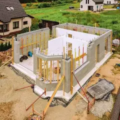 Budowa domu ze styropianu w postępie. Widać fundamenty, ściany z bloczków i elementy szalunku.