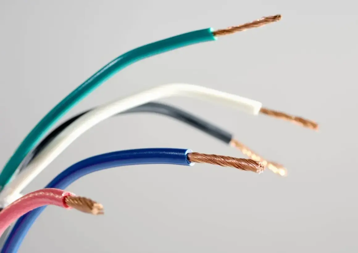 Kolorowe przewody elektryczne, każdy z odsłoniętym miedzianym rdzeniem. Widoczne oznaczenie prądu L na niebieskim przewodzie.