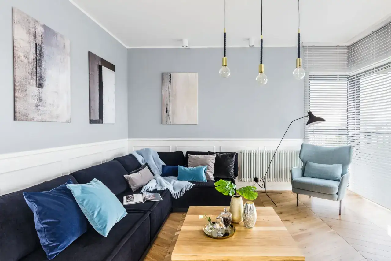 Nowoczesny salon z granatową kanapą i błękitnymi poduszkami. Inspirujące kolory do pokoju, które tworzą spokojną atmosferę.