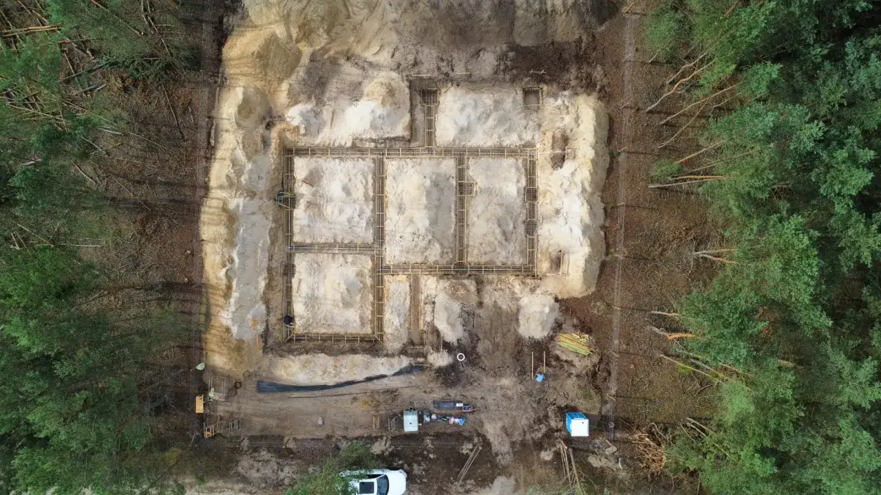 Budowa fundamentów domu w lesie. Widać zbrojenie i szalunki, przygotowane do betonowania. To kluczowy etap badań geotechnicznych gruntu.